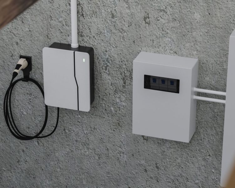 Wall-mounted electric vehicle charging station with black cable and white connector next to white electrical control panel with circuit breakers visible through window, installed on gray concrete wall